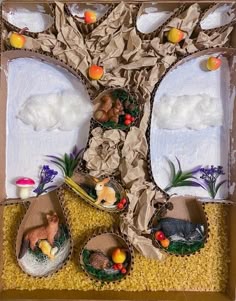 an open cardboard box filled with fake animals and trees on top of yellow carpeted ground