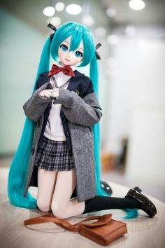 a doll with long blue hair sitting on top of a table