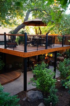 a deck with an umbrella over it surrounded by trees