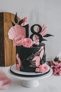 a black and pink birthday cake with flowers on the top is decorated with an 18