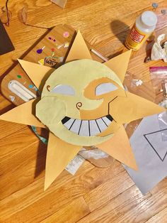 a paper cut out of a smiling face on top of a wooden floor next to craft supplies