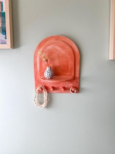 an orange wall shelf with a vase on it