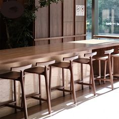 a row of wooden bar stools sitting next to a long counter in front of a window