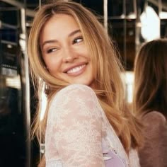 a woman with long blonde hair smiling at the camera