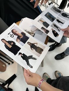 a person sitting at a table holding up an open magazine with photos of people in it