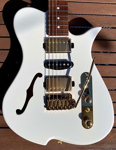 a white electric guitar sitting on top of a wooden table