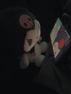 a stuffed animal sitting next to an electronic device in the dark with it's eyes closed