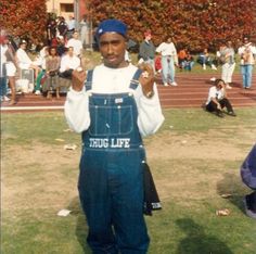 a man in overalls holding up two fingers