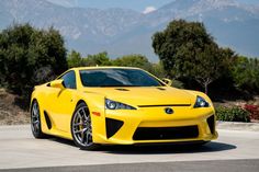 a yellow sports car parked in front of some mountains
