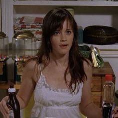 a woman sitting at a table in front of a bottle