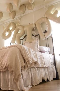 the bed is made with white linens and pillows hanging from the ceiling above it