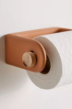 a roll of toilet paper is hanging on the wall next to a brown leather holder