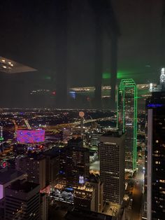 an aerial view of the city at night with lights on and buildings lit up in green