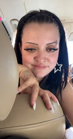 a woman sitting in the back seat of a car with her hand on the steering wheel