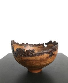 a wooden bowl sitting on top of a black table next to a white wall in the background