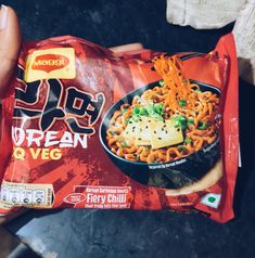 a person holding a bag of frozen veggie ramen noodles in their hand