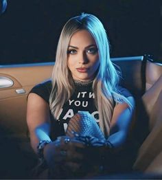 a woman sitting in the back seat of a car with her hand on an object