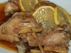 a plate topped with meat covered in gravy and sliced lemons