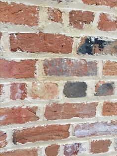 an old brick wall with some paint chipping off the top and bottom part,