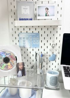 a laptop computer sitting on top of a desk next to a glass shelf filled with personal items