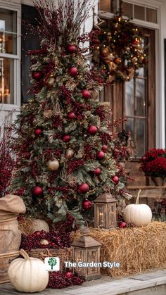 a decorated christmas tree sitting on top of a wooden table next to hay bales