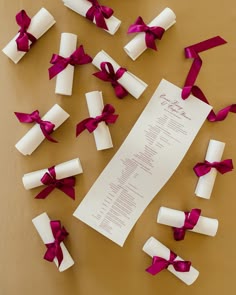 the wedding program is surrounded by red and white paper wrapped in satin ribbons with bows
