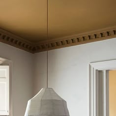 a light fixture hanging from the ceiling in a room with white walls and trimmings