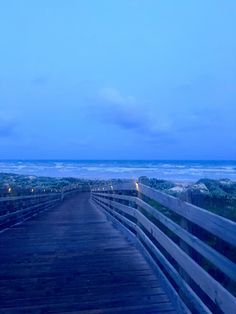 a wooden walkway leading to the beach at night with blue sky and ocean in background