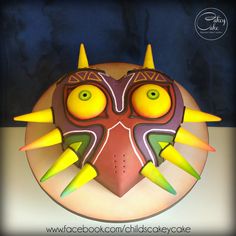 a cake decorated with yellow and green spikes on top of a white plate that has a face made out of icing