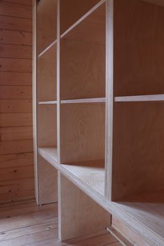 an empty wooden shelf in the corner of a room with wood walls and flooring