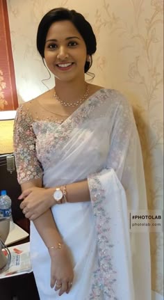 a woman wearing a white sari and smiling