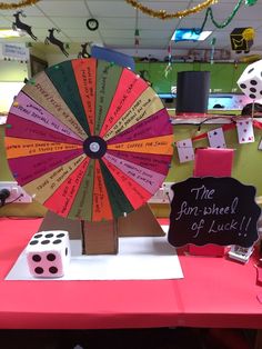 a pink table topped with lots of dice and a spinning wheel on top of it