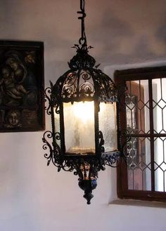 a lamp hanging from the side of a wall next to a window with two paintings on it