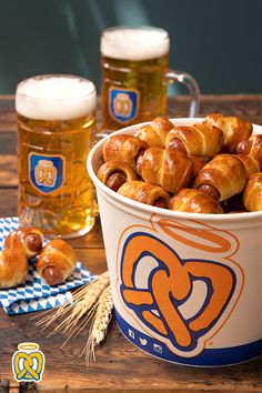 a bowl full of pretzels next to two mugs of beer