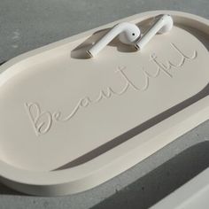 an earphone is sitting on top of a white tray with the word beautiful written in it