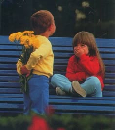 two young children sitting on a blue bench with flowers in their hands and looking at each other