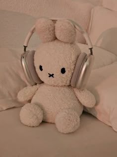 a white teddy bear with headphones sitting on a bed