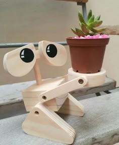 a wooden toy sitting on top of a bench next to a potted plant with eyes