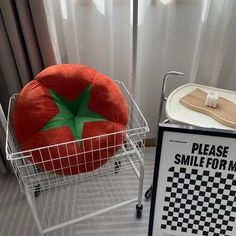 a large tomato shaped pillow sitting on top of a metal basket next to a sign