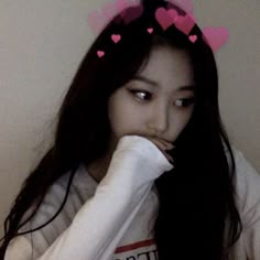 a girl with long black hair wearing a white t - shirt and pink hearts on her head