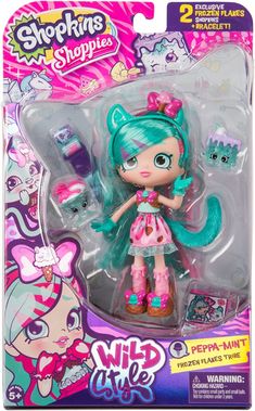 a doll with blue hair and green eyes in a pink outfit on a white background