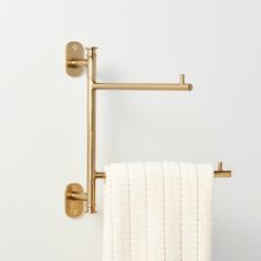 a towel hanging on the side of a wall next to a toilet paper holder with two gold handles
