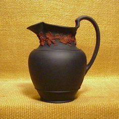 a black vase sitting on top of a yellow cloth