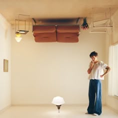 a man standing in an empty room talking on a cell phone