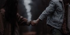 two people holding hands in the woods
