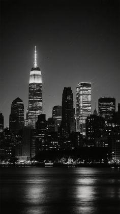 black and white photograph of new york city at night with the empire building lit up