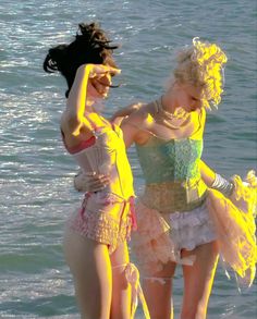 two young women standing next to each other near the water