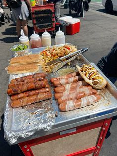 hotdogs and other foods are being prepared on a table at an outdoor event