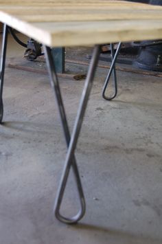 a wooden table with metal legs in a garage