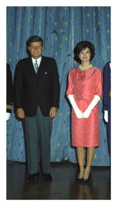 two people standing next to each other in front of curtains